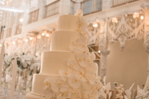 中间的桌子上摆着用鲜花装饰的白色婚礼蛋糕。图片下载