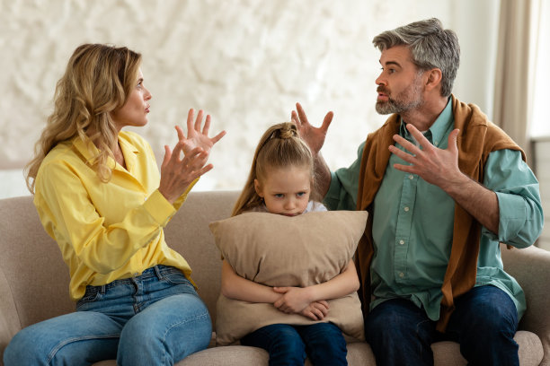 不开心的女儿坐在父母中间，而他们在室内争吵图片下载