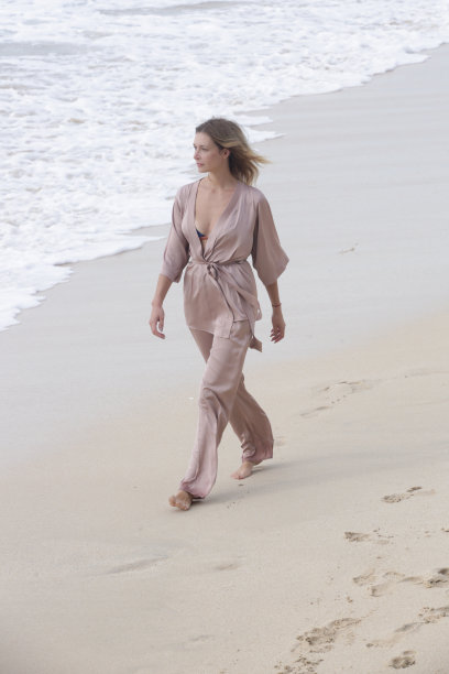 美丽的年轻女子的肖像，米色丝绸服装在空旷的沙滩上，田园诗般的暑假远离城市图片下载