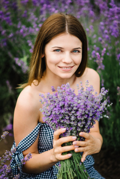 美丽的女孩在紫色薰衣草的田野里穿着裙子。女人走在薰衣草田上。女性收集薰衣草。享受花林间空地，和夏天的大自然。天然化妆品和生态化妆品的概念。图片下载