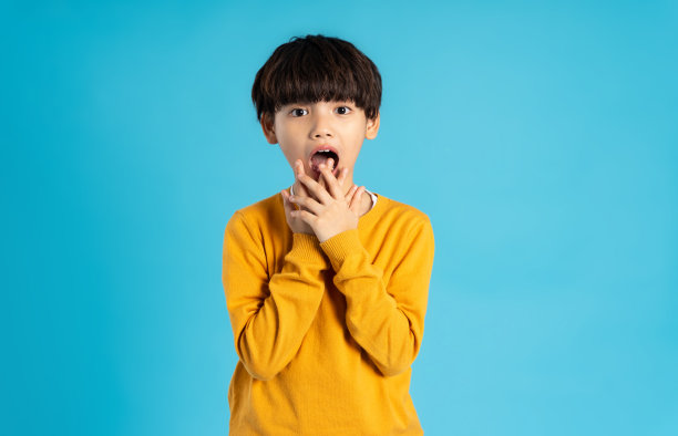 亚洲男孩在蓝色背景上摆姿势的肖像图片下载