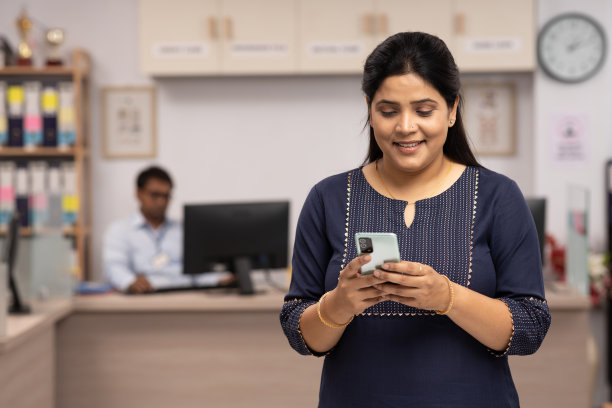 快乐的女人在银行使用电话的肖像。库存图片图片下载