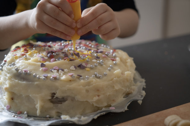 小女孩在生日蛋糕上撒糖。图片下载