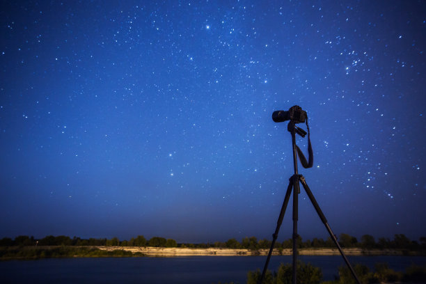 摄影相机在三脚架上的背景上的夜空星空。星星。景观图片下载