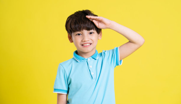 一个亚洲男孩在黄色背景上摆姿势的肖像图片下载