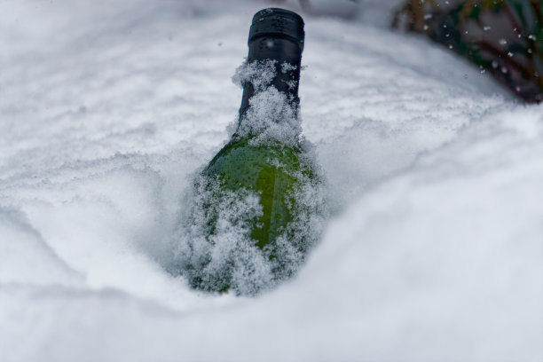 在寒冷的雪地里，一瓶白葡萄酒的特写。图片下载