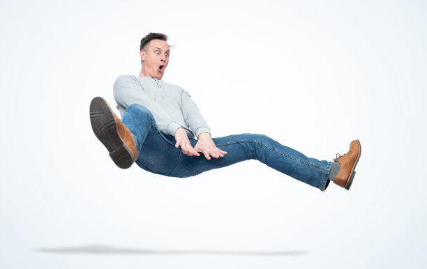 一个穿着便服的滑稽男子正在跳过一个体操障碍，孤立在浅蓝色背景上图片下载