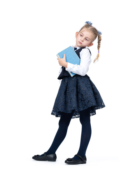 一个穿着校服的小女孩站着摆姿势，手里拿着一本书，孤零零地放在白色背景上。图片下载