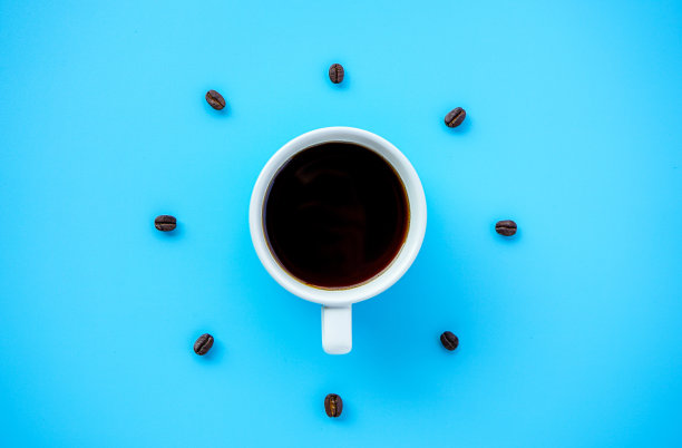 黑色咖啡杯在蓝色背景与咖啡豆排列形成钟面图片下载