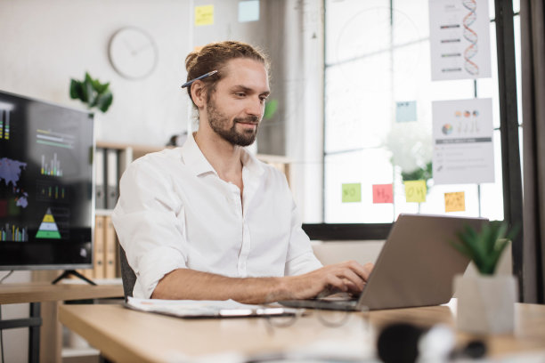 白人男性办公室经理，穿着白衬衫，用无线笔记本电脑写财务报告图片下载