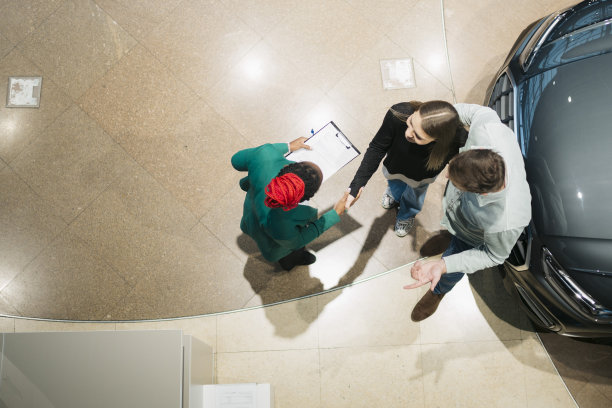 一对夫妇买了新车后在汽车展示厅与经理握手图片下载