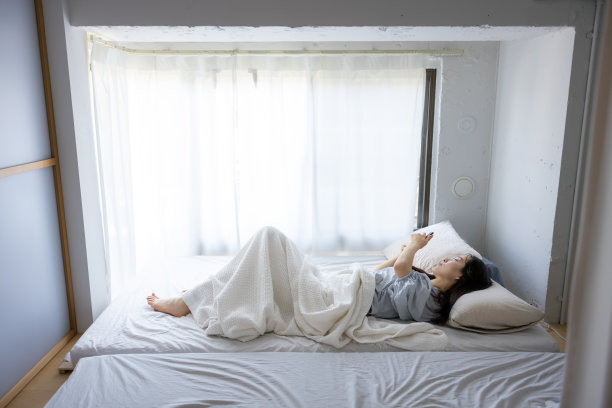 年轻女子早上在床上使用智能手机图片下载