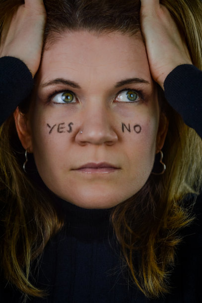 做决定——一个美丽的金发女人的肖像，她的脸颊上写着“是”和“否”，抬头寻找答案图片下载