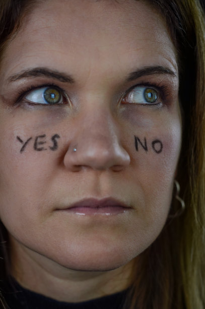 做决定——一个美丽的金发女人的肖像，她的脸颊上写着“是”和“否”，抬头寻找答案图片下载