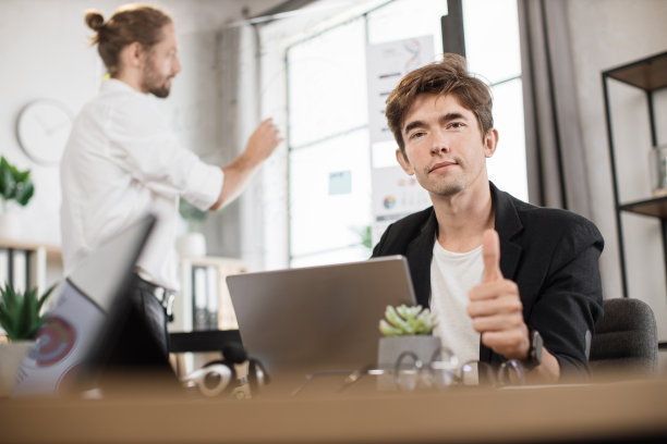 侧视图专注的年轻商人坐在桌子上显示大拇指图片下载