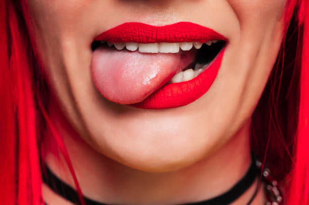 性感的女性嘴唇。有趣的张开嘴，舌头伸出来。一个微笑的年轻女孩。漂亮的脸特写。图片下载
