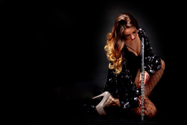 性感封面女士长笛手摆出长笛在黑色孤立的背景，看着相机。别致的女艺术家在黑色服装与长笛在手中。管弦乐队的音乐概念。复制文字空间，广告海报图片下载