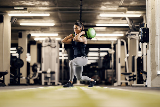 在健身房里，一位女健身运动员正扛着重物做弓步。图片下载