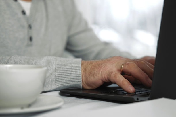 老年男子使用笔记本电脑的特写镜头。裁剪的侧面视图，皱白种人的老手打字键盘。有科技的老人。面目全非的退休男性，坐在办公桌前在家工作图片下载