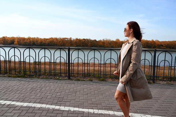 一个自信的年轻迷人的女人穿着外套和高跟鞋走在城市的街道上，女人微笑着享受生活图片下载