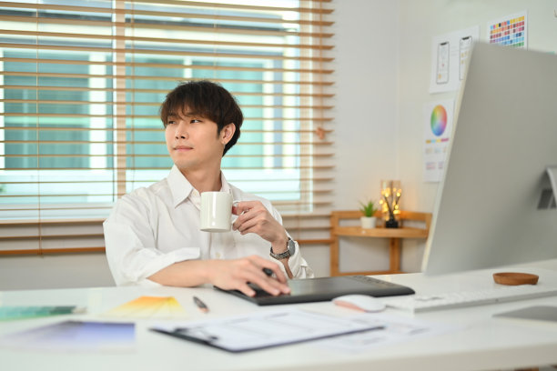 深思熟虑的亚洲男子网络开发人员喝咖啡，透过窗户，思考想法在办公室。图片下载