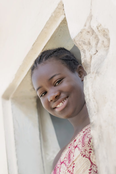 年轻的非洲女孩站在家门口，微笑的表情，照片图片下载