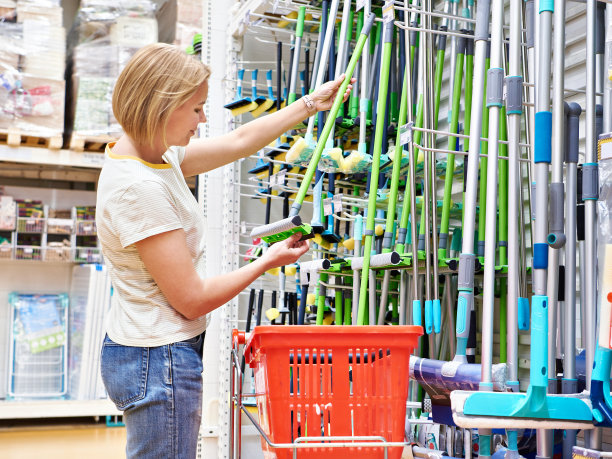 一个女人在商店里买拖把打扫卫生图片下载