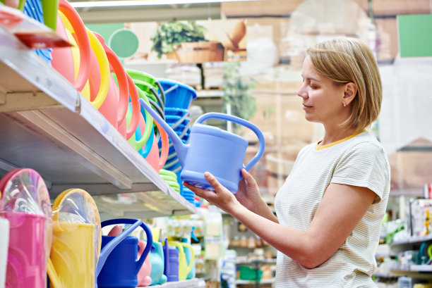 一名妇女正在挑选商店里的花园浇水罐图片下载