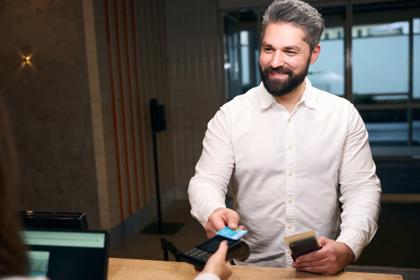 快乐的企业家在前台支付酒店房间图片下载