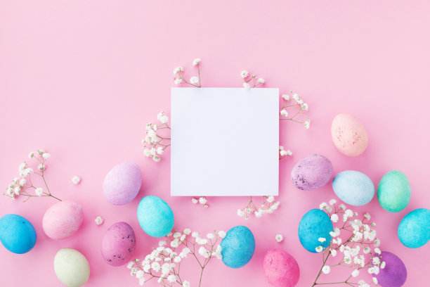 复活节假期概念。俯视图照片的彩色复活节彩蛋，空纸卡和白色的吉卜草花在粉红色的桌子上。图片下载