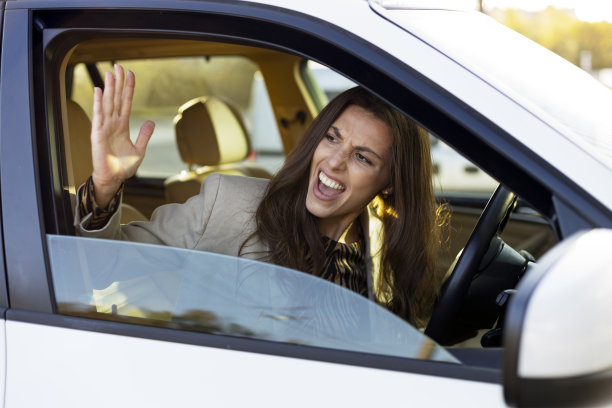 一个迷人的女人在方向盘后面争论，争吵。讨厌的女孩开车。图片下载