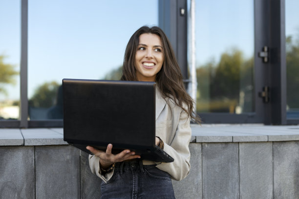 年轻漂亮的女商人在户外使用笔记本电脑，在线学习，在互联网上工作。图片下载
