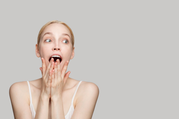 兴奋震惊的妇女与健康的清晰新鲜的皮肤对灰色的工作室墙旗帜白色背景图片下载