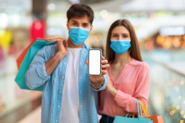 一对戴着口罩的夫妇在商场购物，显示智能手机屏幕图片下载