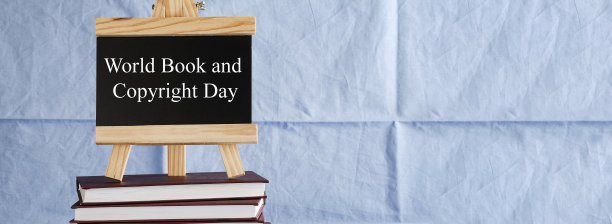 “世界图书和版权日”写在黑板上，蓝色背景的书堆上。读书假日，教育理念旗帜图片下载