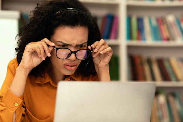 专注的戴眼镜混血女人在图书馆使用电脑图片下载