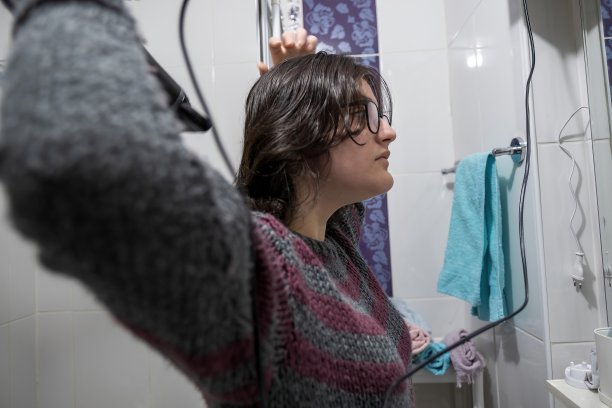 青少年女孩在浴室用吹风机吹干头发图片下载