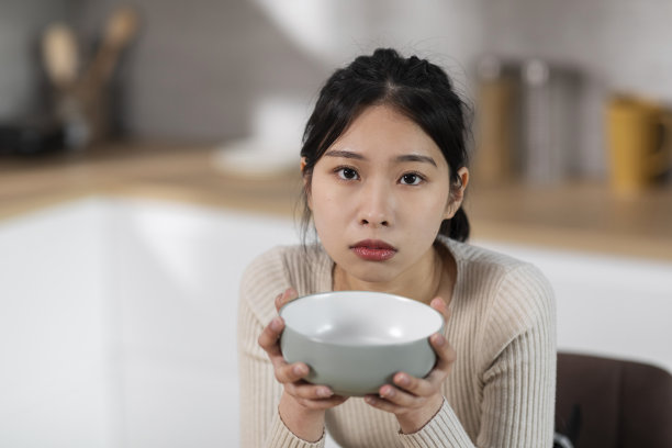 饥饿的亚洲女人把空盘子放在嘴边图片下载