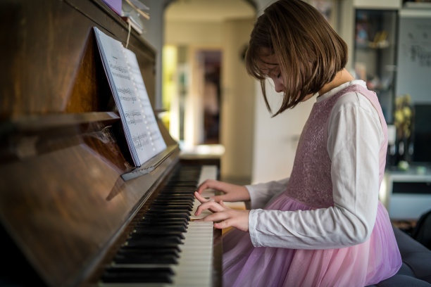 可爱的女孩在家里弹钢琴图片下载