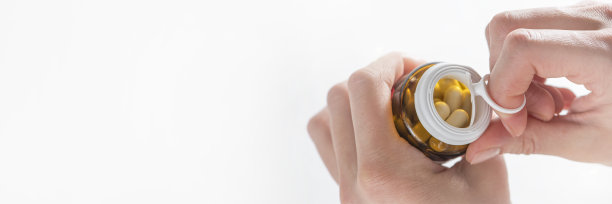 安眠药，服用安眠药治疗失眠和中枢神经系统过度兴奋。一个女人的手在白色背景下打开了一瓶安眠药。图片下载