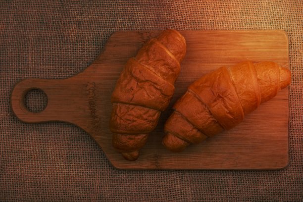 在布袋背景上的切菜板上的羊角面包的俯视图图片下载