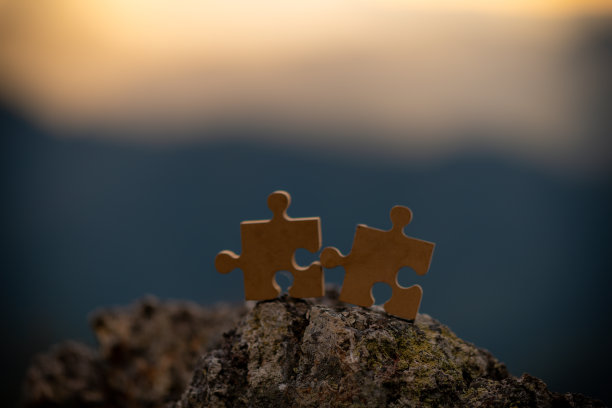 连接夫妇拼图与日落的背景。空拷贝空间。在阳光下玩拼图游戏。整体的一部分关联和连接的符号。商业策略。图片下载