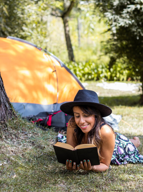 一个阳光灿烂的日子里躺在草地上看书的女人图片下载