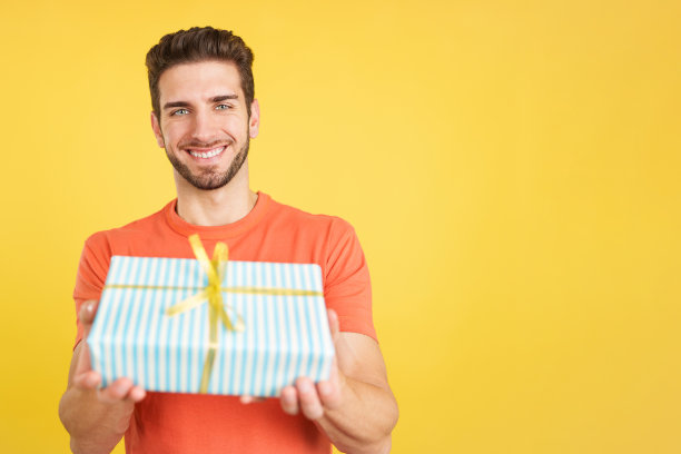 快乐的男人看着镜头送礼物图片下载