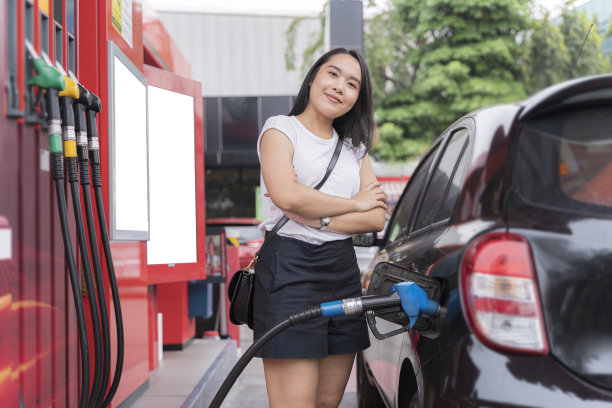 汽车加油站加油站一位可爱的女士站在那里，微笑着给油嘴加油。运输图片下载