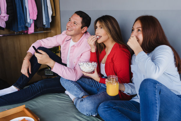 一群最好的西班牙朋友坐在床上看电视或电影在墨西哥拉丁美洲的家里图片下载