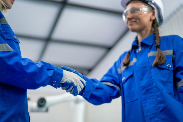 近距离的白人工程师或技术人员与她的同事握手，以表达机器人机器项目在工作场所的成功。图片下载