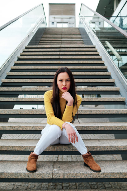 一名女子坐在室外的楼梯上看着摄像机。图片下载