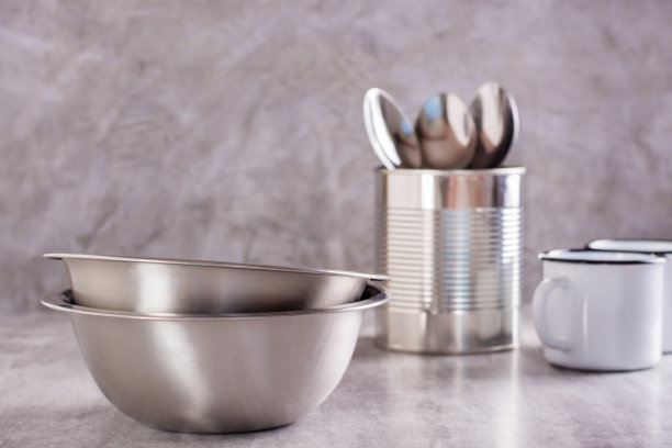 两个空金属碗，罐子里的勺子和灰色背景的金属搪瓷马克杯图片下载