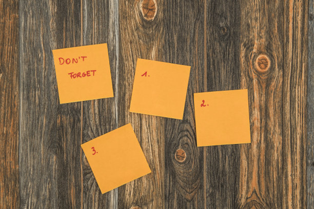 棕色木质背景上的橙色便签，上面有别忘了的文字，还有三个空白的便签，上面写着从1到3的数字。图片下载